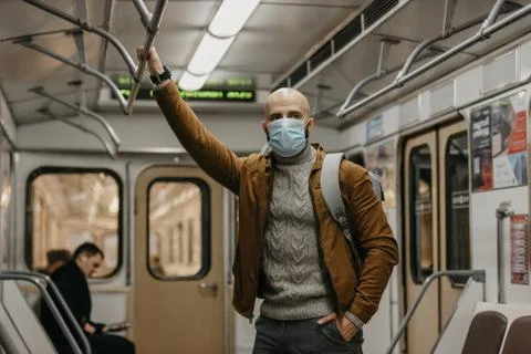 Man in a face mask to avoid the spread of coronavirus is riding in a subway c Stock Photos