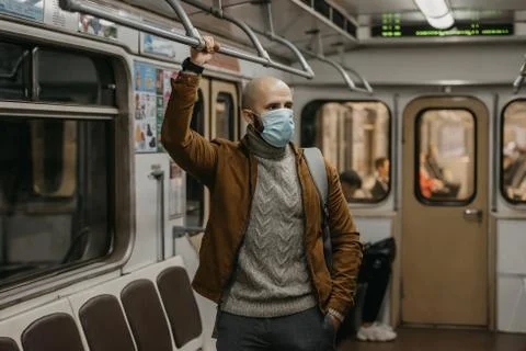 Man in a face mask to avoid the spread of coronavirus is riding in a subway c Stock Photos