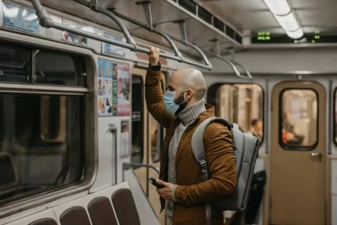 Man in a face mask to avoid the spread of coronavirus is riding in a subway c Stock Photos