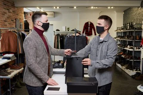 Man in a face mask to avoid the spread of coronavirus is handing a credit car Stock Photos
