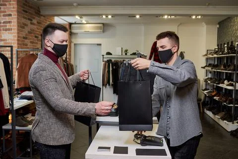 A man in a face mask to avoid the spread of coronavirus is taking his purchas Stock Photos