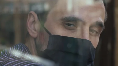 Man in face mask behind the the window Video stock 129802715