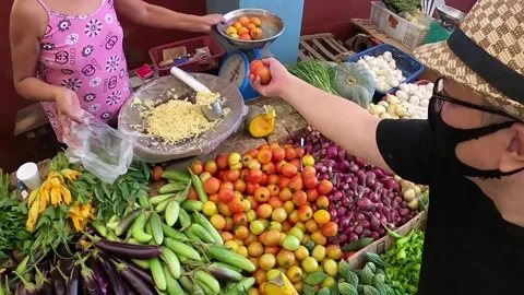 MAN WITH FACE MASK BUYS VEGETABLES AT MARKET IN ASIA Stock Footage 159803213