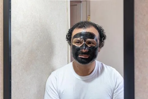 Man with face mask looking at himself in the mirror Foto stock