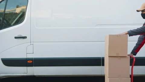 Man with face mask pushing cardboard boxes on the troley. Delivery of parcels Stockbeeldmateriaal 150653100