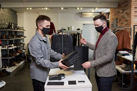 A man in a face mask is taking his purchases from a shop assistant in a store Stock Photos