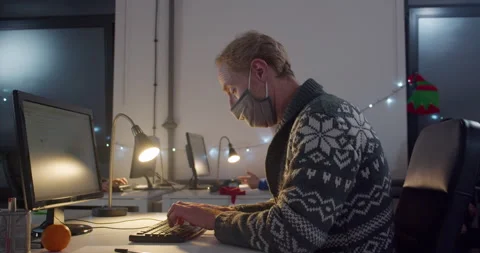 Man in face mask working on computer at desk at night Video stock 144271125