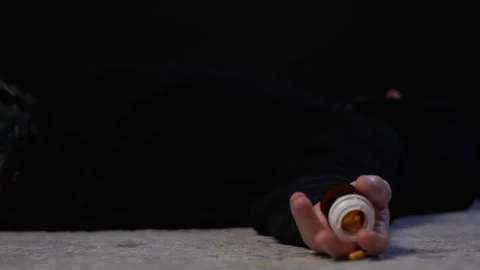A man fall down on a floor with a bottle of pills in his hand Stock Footage 271243649