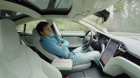 Man falling asleep behind the wheel in self-driving autonomous electric car Stock Footage 72880648