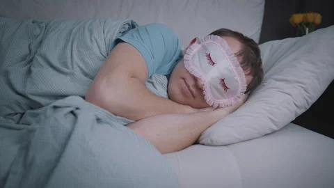 Man Falling Asleep on Cozy Sofa with Sleep Mask Stock Footage 334320848