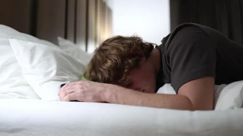 Man falling asleep while holding smartphone showing exhaustion and internet addi Stock Footage 318778786