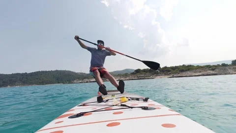 Man falling from stand-up paddleboard into the sea, captured at the exact moment Stock-Footage 313843699