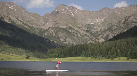 Man falls off paddle board in mountain lake Stock Footage 56563768