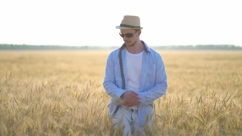 Man farmer in a hat walking in wheat field Stock Footage 134832711