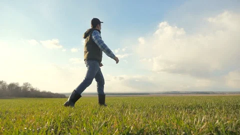 Man farmer red a neck in cap is walking on a green field. spring harvest Stock Footage 129581944