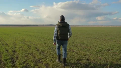 Man farmer red neck in a cap lifestyle is walking on a green field. spring Stock Footage 136459848