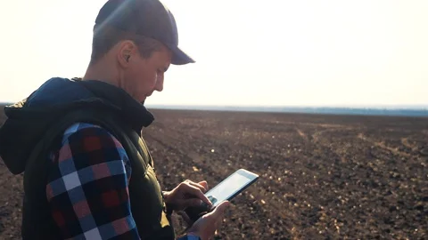 Man farmer red neck with a digital tablet walking on land for sewing on a soil Stock Footage 127910966