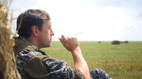 The man the farmer sits at a haystack, has a rest, looks at the done work. close Stock Footage 98937511