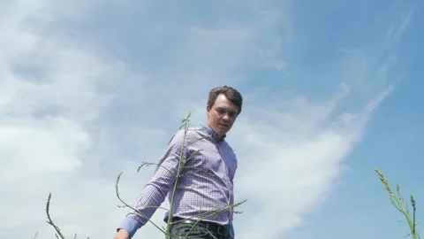 A man farmer walks through a field of asparagus and touches the vegetables with 動画素材 130404346