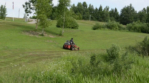 Man fast driving cut grass lawn mower tractor in resort park Stock Footage 32419558