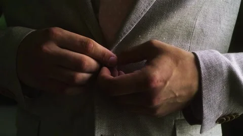 A man fastens a button on his jacket. the guy is wearing a tuxedo.  Stock Footage 279879829