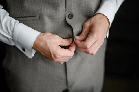 A man fastens a button on his jacket, close-up.A man in an elegant classic suit. Stock Photos