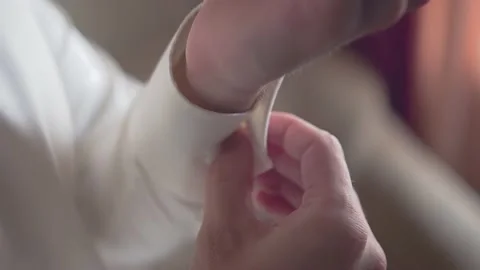 A man fastens a button on the sleeve of a white shirt Video stock 222643272