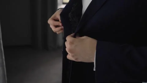 The man fastens the buttons of his jacket. The jacket is blue. Close-up shooting Stock Footage 250484086