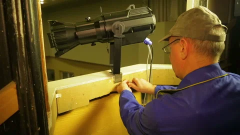 A man fastens a fastening ring to the wall for a safety wire of a theatrical Video stock 104207311