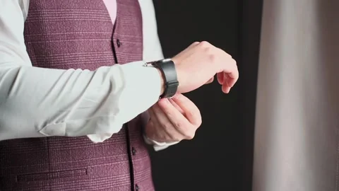 A man fastens his watch strap while standing by the window Video stock 328299511