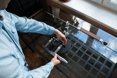 Man fastens a kitchen knife into a precision sharpener. Male user setting 스톡 사진
