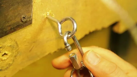 The man fastens to the mounting ring in the wall a safety cable for theatrical Stock Footage 104207450