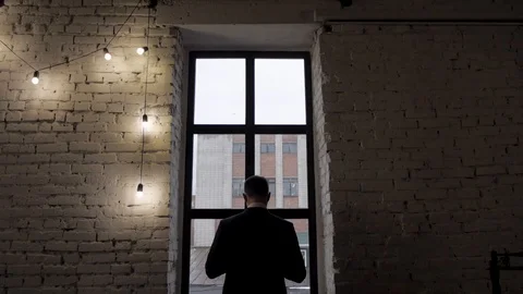 Man fastens suit by the window, view from the back Stock Footage 122234688