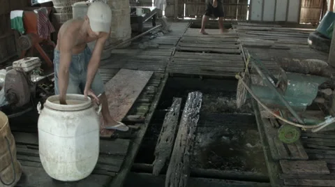 A man feeding fish in a pen at a fish farm on the Mekong River in Vietnam Stock Footage 48165552
