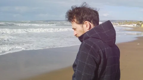 Man feeling alone and sad in front of the ocean in winter slow motion Stock Footage 118393775