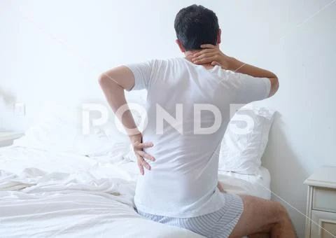 Man feeling back ache in the bed after sleeping Stock Photos