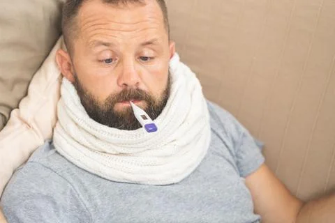 Man feeling bad lying in bed and looking the thermometer , main focus on the  Stock Photos