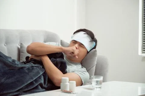 Man feeling bad lying in the couch and coughing Stock-Fotos