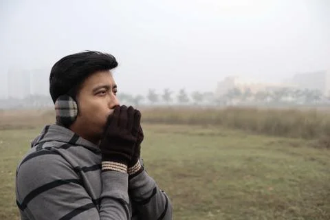 A man feeling cold being dressed in winter garments and gloves with focus on Stock Photos