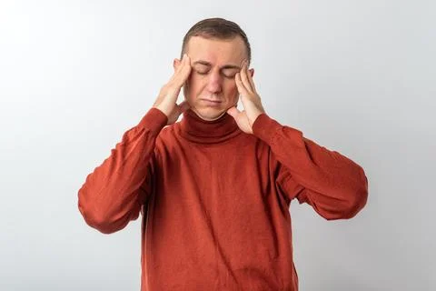 Man feeling intense headache and overwhelming stress, pressing his temples .. Stock Photos