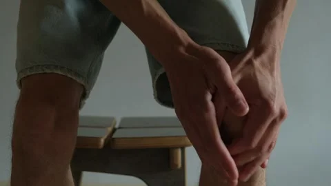 Man feeling knee pain while standing up, close-up on gray background. Stock Footage 310946451