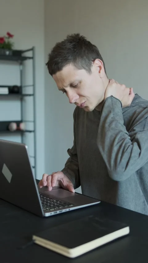 Man feeling neck pain while working on laptop. Uncomfortable working position Stock Footage 309205236