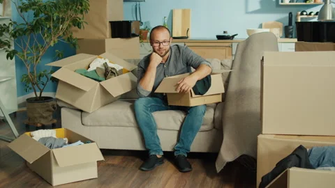 Man Feeling Overwhelmed While Packing for Move, Surrounded by Open Boxes at Home Stock Footage 311579400