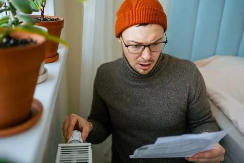 Man feeling shocked and stressed, holding an expensive heating bill in his Stock Photos