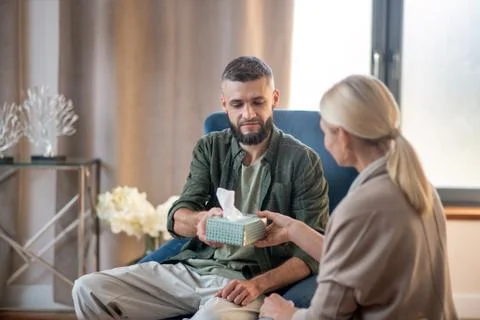 Man feeling thankful while taking napkins from psychologist Stock Photos