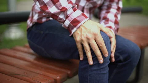 Man feels knee pain, sprained ligaments, dislocated kneecap, spot indicates ache Stock Footage 94351829