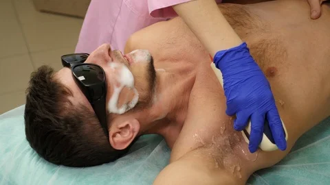 Man feels pain while getting permanent laser hair removal at beauty salon Stock Footage 102400132