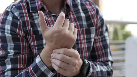 A man feels a sharp pain in his hand and massages it to relieve the pain. Stock Footage 254163388