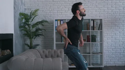 Man felt back pain getting up from the couch Stock Footage 145699346