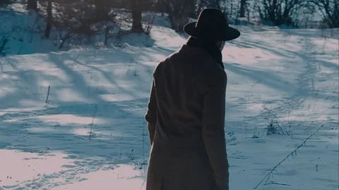 A man in a felt hat and coat comes in the winter woods. brown hat made of felt Vidéo 72411007
